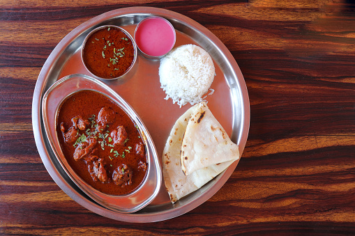 Malvani chicken Thali. It is a popular Indian or Konkani food platter that includes Chicken curry, egg curry, Rice bhakri, Steamed Rice, Solkadhi, and salad. Copy space.