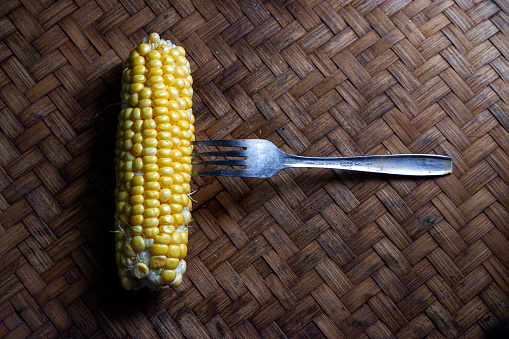 a corn pierced with a fork, a fork stuck into a corn