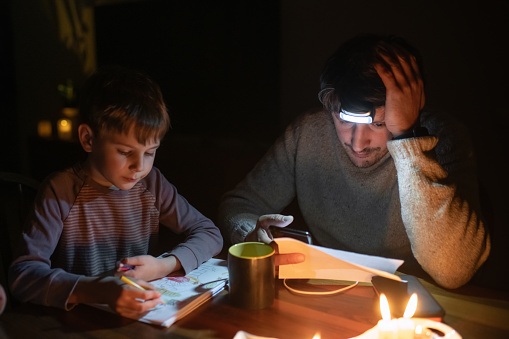 Family sitting at home with candles during blackout.