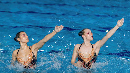 Artistry of synchronized swimming duet delivers a stunning performance, blending elegance and precision,