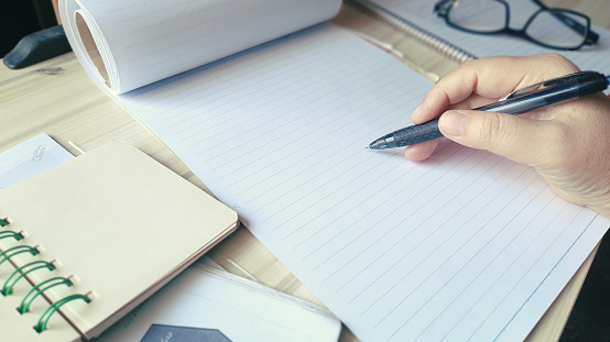 Businesswoman holds a pen in hand to take notes during a meeting, seminar online, remote learning.