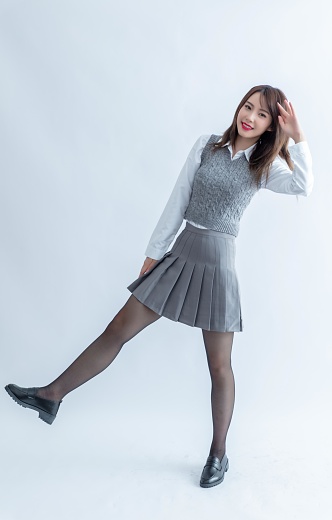 Asian school girl in grey skirt and white blouse posing