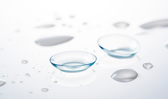 Soft contact lenses placed on a white background with water droplets. Image of a contact lens.