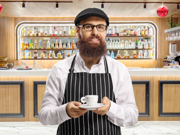 Barista with an apron and an espresso coffee at a bar