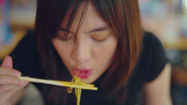 Young asian woman enjoying with noodle in local restaurant.