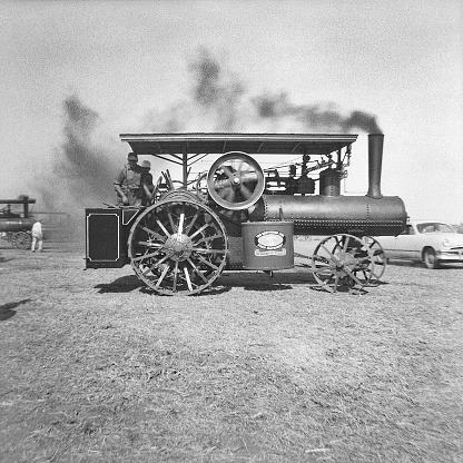 Cedar Falls, Iowa, USA - August 23, 1958: Greyhound steam traction engine being driven in the Threshermen's Field Days parade. A steam engine like this would have been used to power a threshing machine or other farm machinery. Although steam engines and steam tractors were used in the US until the late 1930s and early 40s, collector goups were already forming by the time this photo was taken in 1958 to preserve steam engines and tractors. Scanned film with grain.