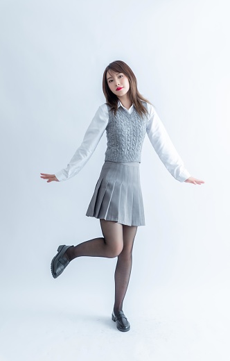 Asian school girl in grey skirt and white blouse posing