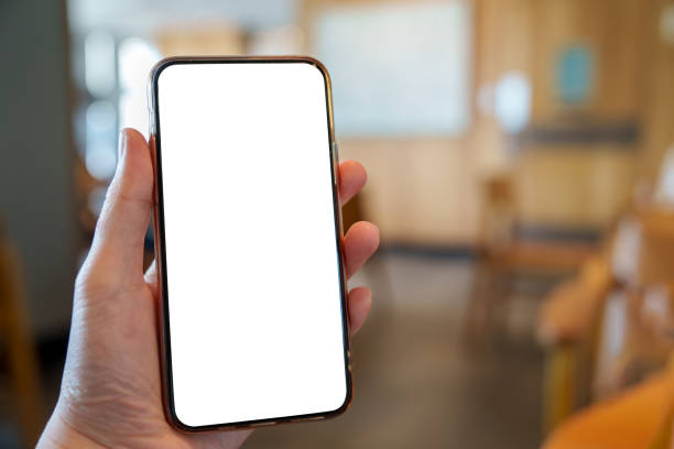 istock Person holding mobile phone with white empty blank screen on blurred office room background. Smartphone display mockup with blank white screen for mobile App Advertisement, Social media content. 1954209249