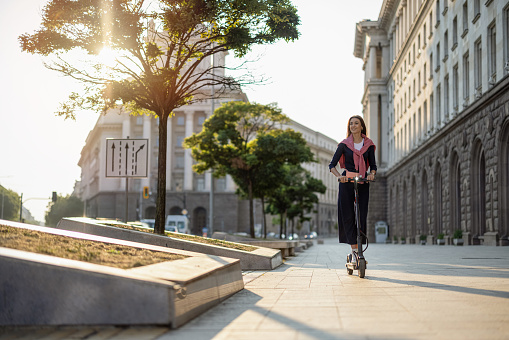 Young woman commuting the city with electric scooter