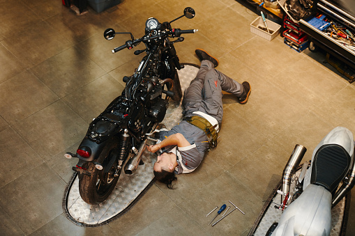 Mechanic lying next to motorcycle when repairing vehicle