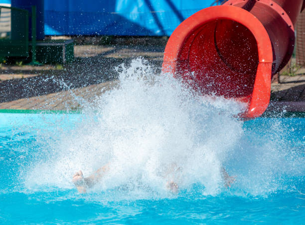 A man flies from a slide into a swimming pool.