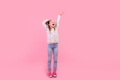 Full size photo of impressed schoolgirl dressed dotted pullover holding palm on head compare height isolated on pink color background.