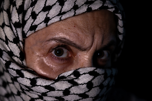 portrait of pearson wearing white keffiyeh on dark background with anger expression on his eyes
