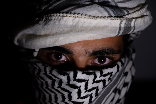 portrait of pearson wearing white keffiyeh on dark background with anger expression on his eyes photo