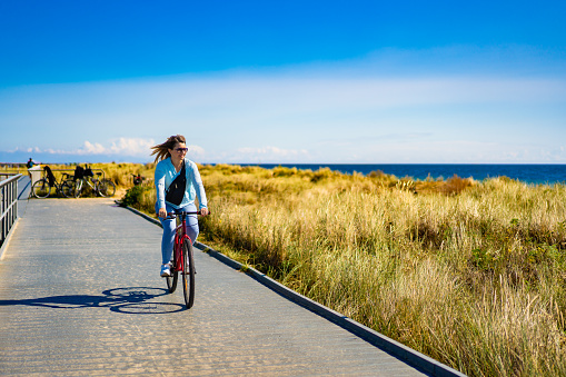 Mid adult woman riding bicycle at seaside