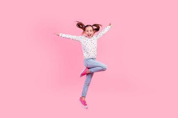 istock Full size photo of optimistic schoolgirl dressed dotted pullover denim pants fly hold arms like wings isolated on pink color background 1954257647