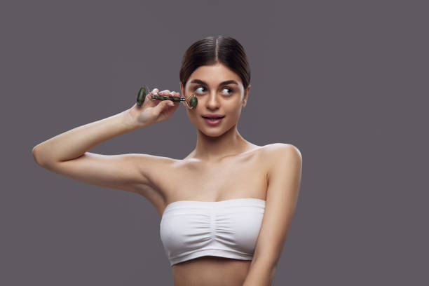 istock Young brunette woman using roller from natural stone, and massaging face to smooth wrinkles and prevent double chins. 1954263670