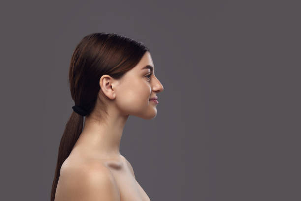 istock Side view of young brunette woman with ponytail and bare shoulders, doing exercises for prevent double chin against neutral background. 1954263701