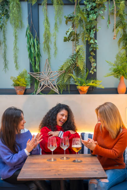 istock Women having fun singing and drinking wine in a cafeteria 1954265817