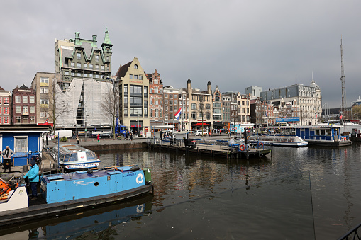 Amsterdam, Netherlands - April 21, 2023: A general view of  the canal cruises pier at the Damrak canal downtown Amsterdam.