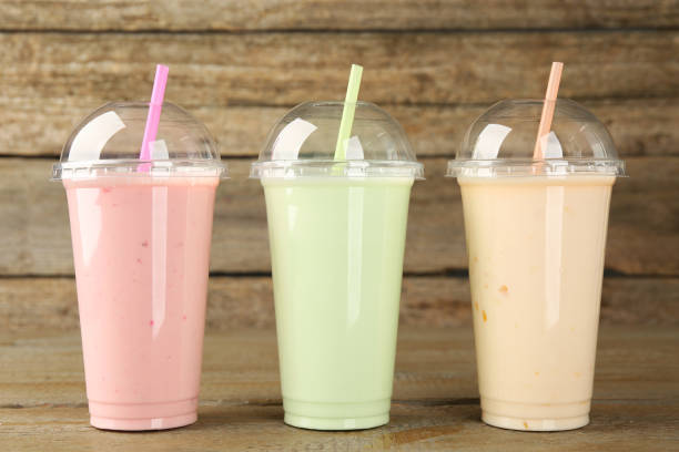 istock Plastic cups with different tasty smoothies on wooden table 1954298062