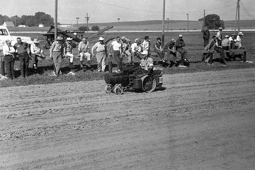 Cedar Falls, Iowa, USA - August 23, 1958: miniature model steam traction engine being driven in the Threshermen's Field Days parade. Although steam engines and steam tractors were used in the US until the late 1930s and early 40s, collector groups were already forming by the time this photo was taken in 1958. Scanned film with grain.