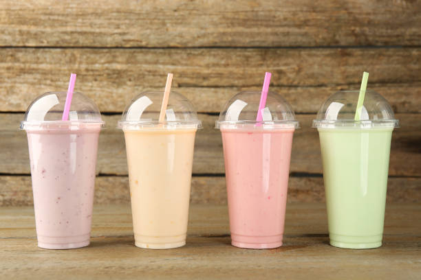 istock Plastic cups with different tasty smoothies on wooden table 1954302916