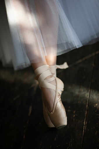 Legs of a dancing ballerina in satin pointe shoes.