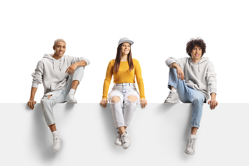 Generation z young people from different race sitting on a blank panel isolated on white background