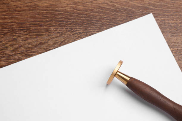 istock One stamp tool and sheet of paper on wooden table, top view. Space for text 1954333413