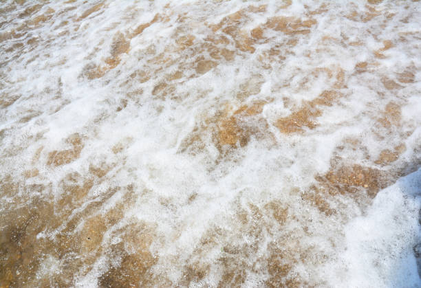 istock White light seafoam waves on the golden sand beach. 1954334459