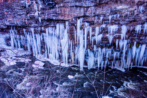 A beautiful winter scene featuring a cliff adorned with sharp icicles
