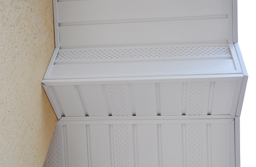 A close-up of a white uPVC soffit,  installed along the roofline of the house. Plastic soffit board below the facia of the roof.