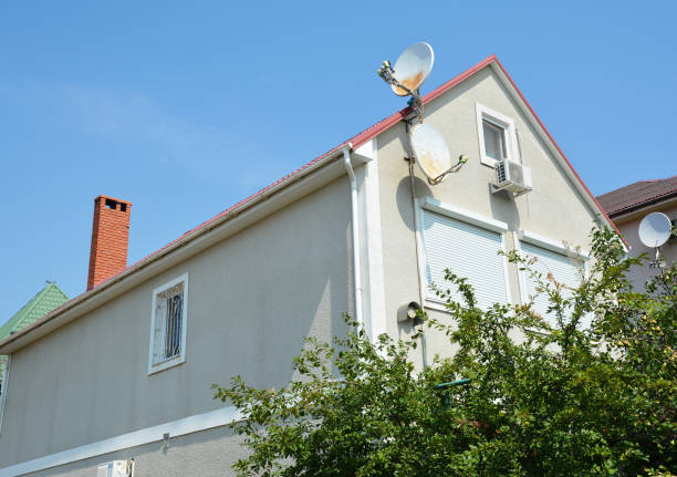 A stucco house with a blind wall but for one small window and a wall with large windows, closed with external roller shutters.