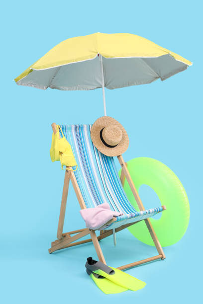 istock Deck chair, umbrella and beach accessories against light blue background. Summer vacation 1954353887