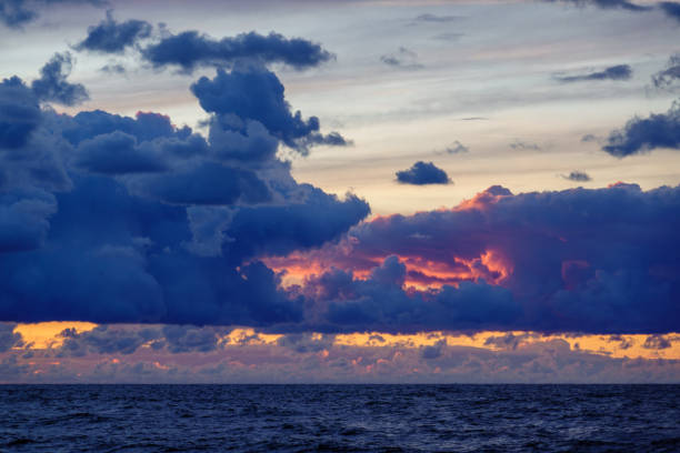 Dramatic ocean sunset with vibrant cloudscape, reflecting serene twilight hues over tranquil sea