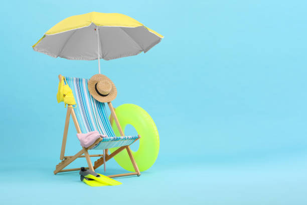 istock Deck chair, umbrella and beach accessories against light blue background, space for text. Summer vacation 1954356561