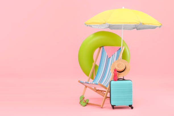 istock Deck chair, umbrella, suitcase and beach accessories against pink background, space for text. Summer vacation 1954356573