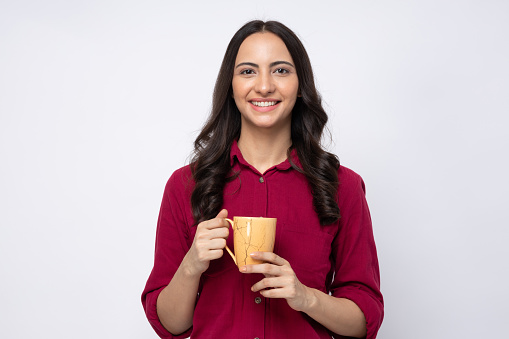 Portrait of young woman drinking hot coffee in white background