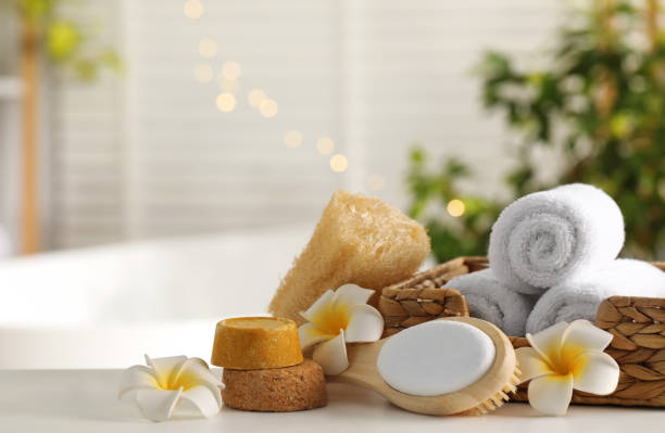 istock Composition with different spa products and plumeria flowers on white table in bathroom. Space for text 1954361571