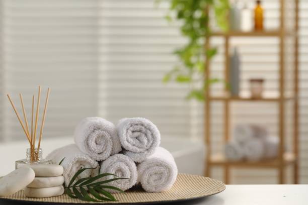 istock Spa composition. Towels, reed diffuser, stones and palm leaves on white table in bathroom, space for text 1954361729