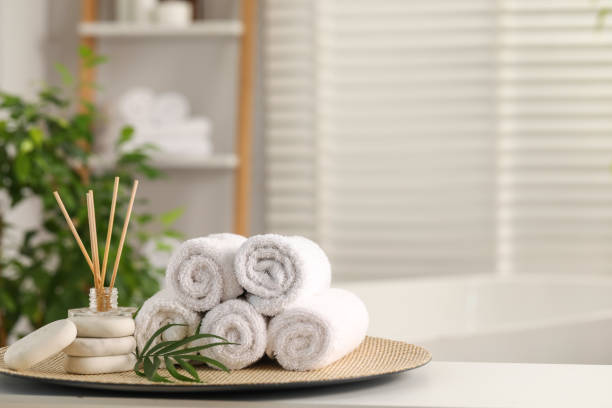 istock Spa composition. Towels, reed diffuser, stones and palm leaves on white table in bathroom, space for text 1954361797