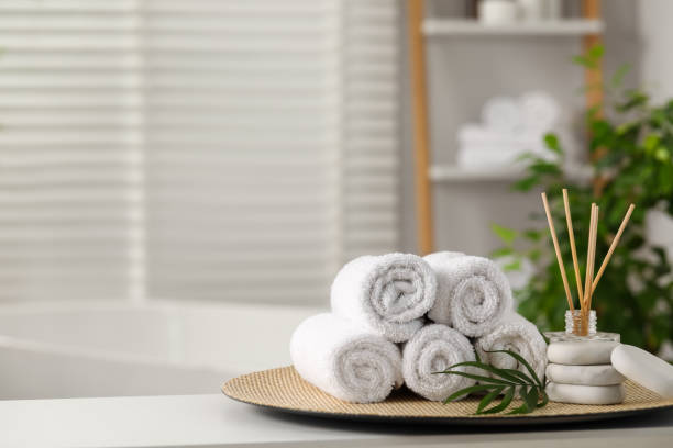 istock Spa composition. Towels, reed diffuser, stones and palm leaves on white table in bathroom, space for text 1954361822