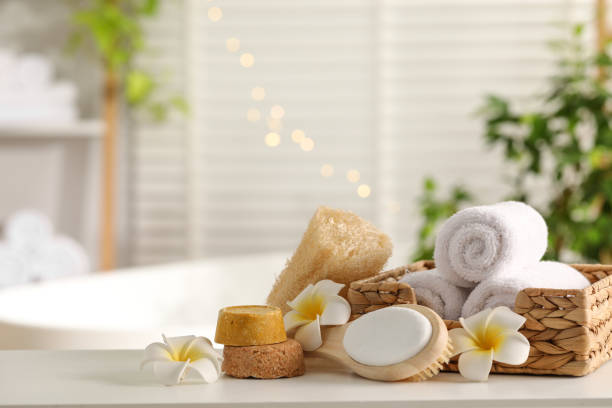 istock Composition with different spa products and plumeria flowers on white table in bathroom. Space for text 1954361855