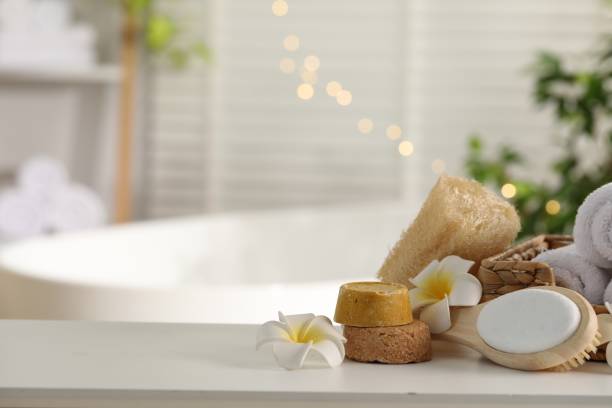 istock Composition with different spa products and plumeria flowers on white table in bathroom. Space for text 1954361872