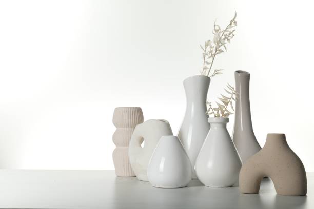 istock Different stylish vases and dried flowers on light table against white background, space for text 1954362161