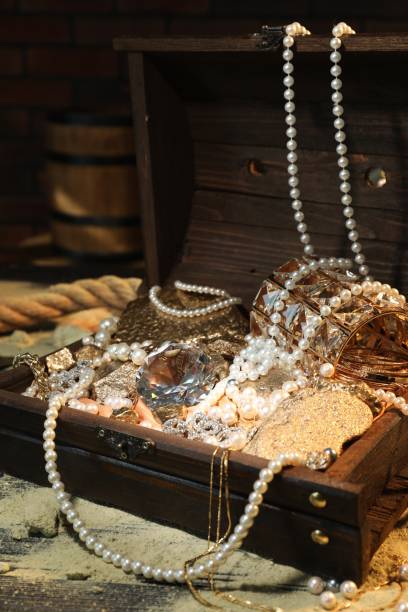 istock Chest with treasures and scattered sand on wooden table 1954362354