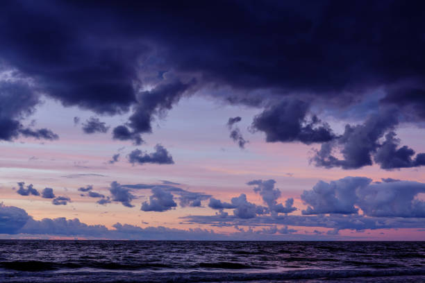 Twilight seascape with layered clouds, radiant sunset hues casting over the undulating ocean