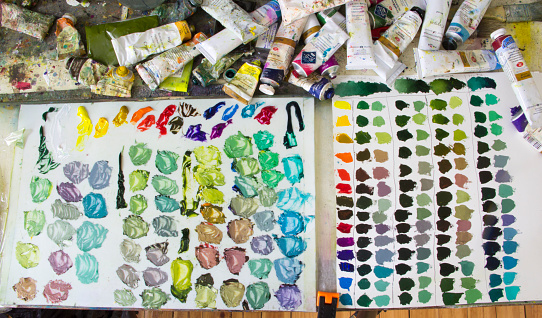 Palette of the artist with multi-colored oil paints. Training of painting. Mixing different colors of paint on the palette.