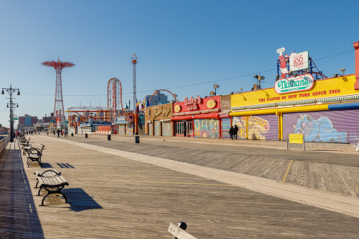 New York City, Brooklyn, USA - February 18, 2023: street atmosphere in front of closed Coney Island attractions with people walking on a winter day